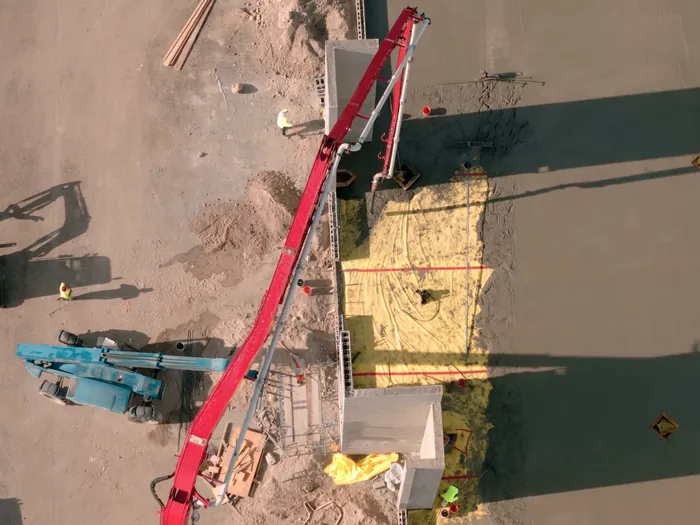 Boom pump line over a freshly placed house slab with crew running power trowels