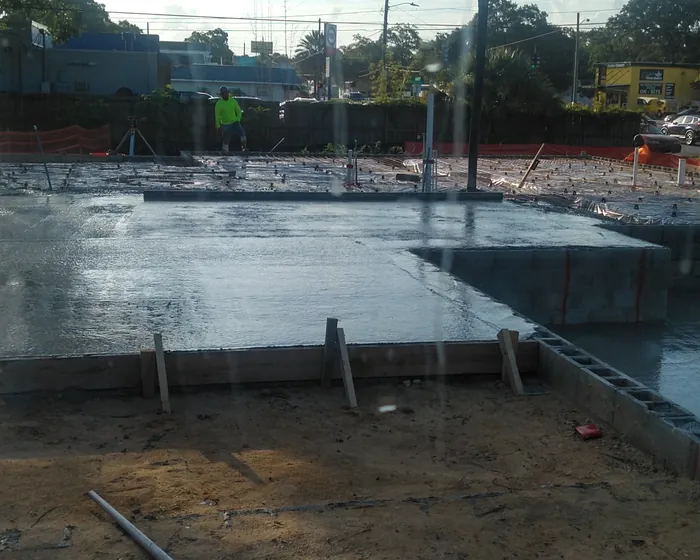 Wide wet concrete slab poured to a street frontage with forms and dowels along the edge