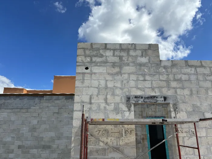 Concrete block walls rising above a finished foundation under a blue sky
